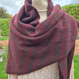 A chunky knit cowl neck scarf with alternating thick stripes of deep burgundy and dark charcoal grey.