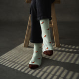 Person wearing light blue socks with pheasant  pattern sitting on a wooden stool.